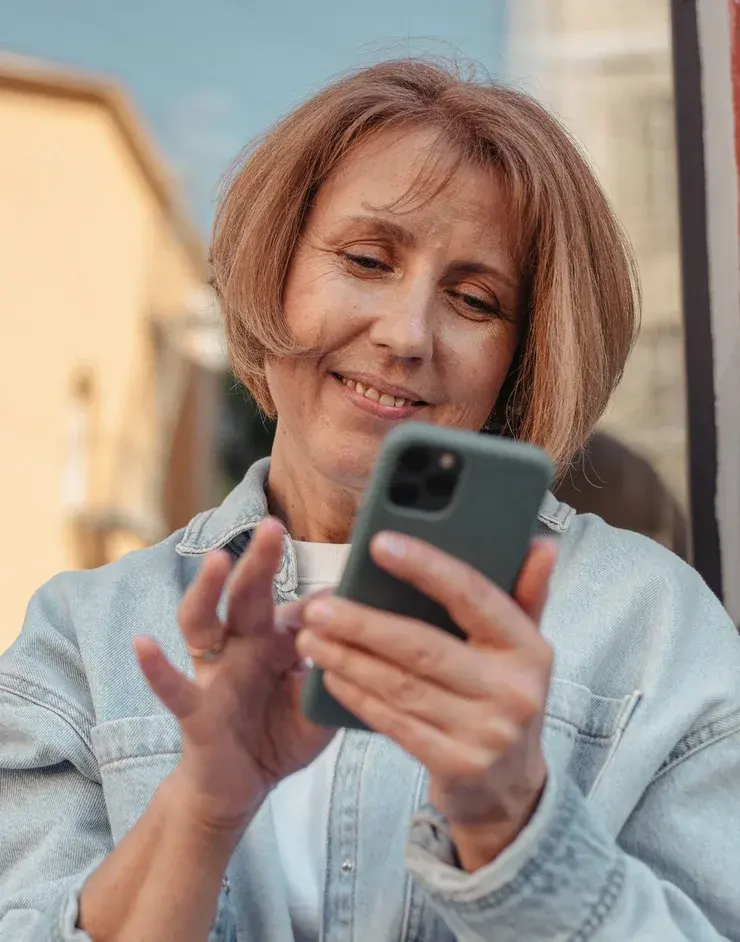 A woman smiling as she reads something on her phone