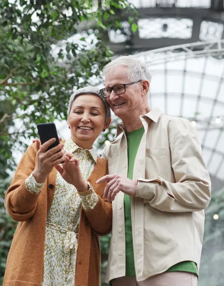 An older couple looking at a phone together outdoors